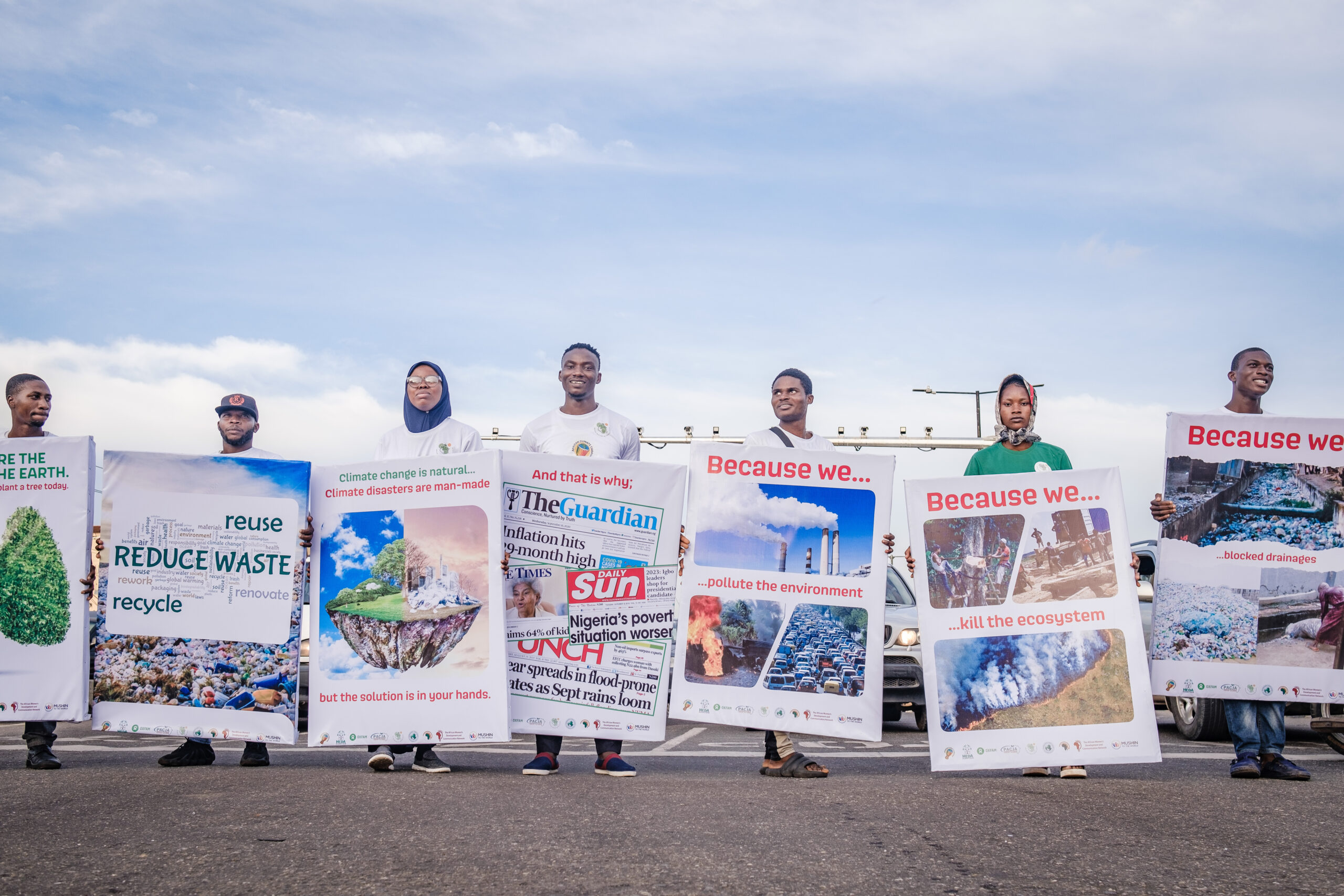 LAGOS, NG - OCTOBER 13, 2022: Volunteers carrying printed infographics in front of the cars stopped by the traffic light at the caravan climate change walk on October 13, 2022 in Allen junction, Ikeja, Lagos State, Nigeria. CREDIT: Taiwo Aina for Oxfam Novib